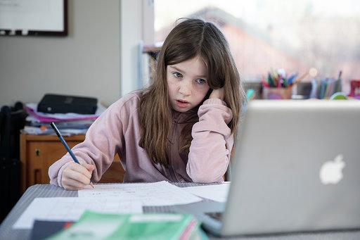 Jente som gjør skolearbeid mens hun ser på en PC