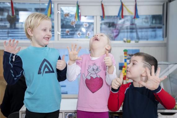 Tre barn som ler og teller på fingre