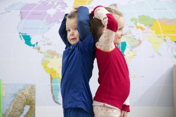 Bilde av jente og gutt som måler lengde foran et verdenskart