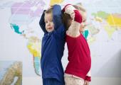 Bilde av jente og gutt som måler lengde foran et verdenskart
