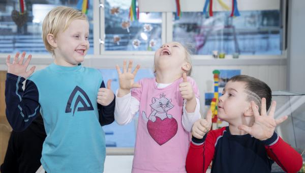 Tre barn som ler og har thupmbs up